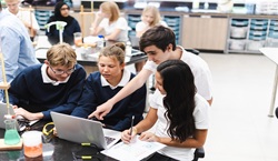 Secondary school pupils sat together in class working on a science experiment
